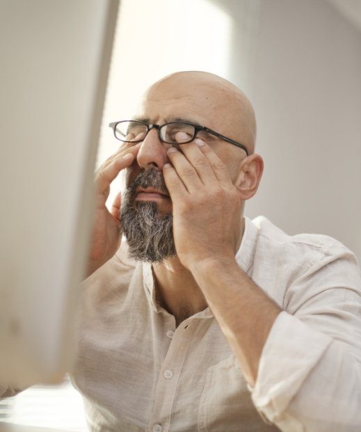 Man rubbing his eyes due to exhaustion from obstructive sleep apnea in Dallas